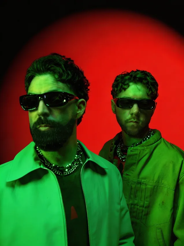 Both members of HILLS wearing sunglasses under red and green lighting