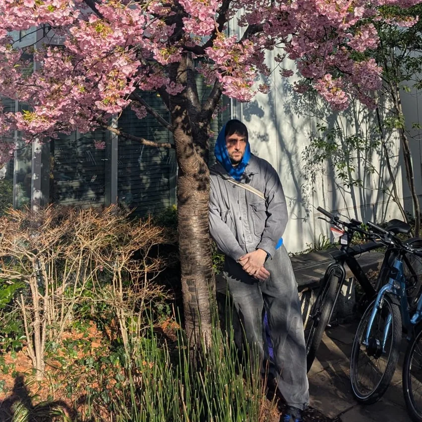 John Talabot standing beneath a flowering tree