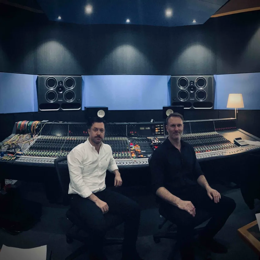 Planet Of Souls members Paul Rogers and Tom Barlow seated together at a studio mixing console