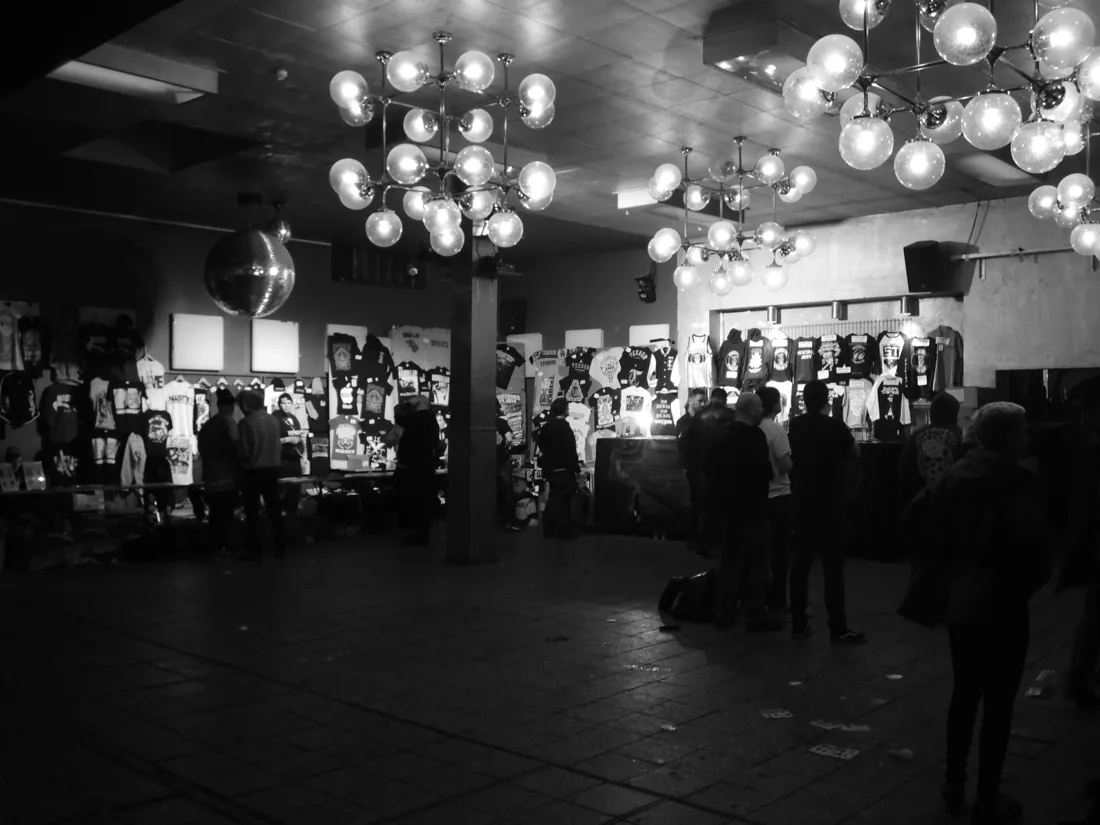 Astra Kulturhaus interior with globe chandeliers and merch stalls, black and white
