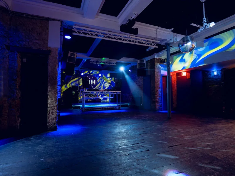 Basing House club room with BH-branded DJ stage and brick walls