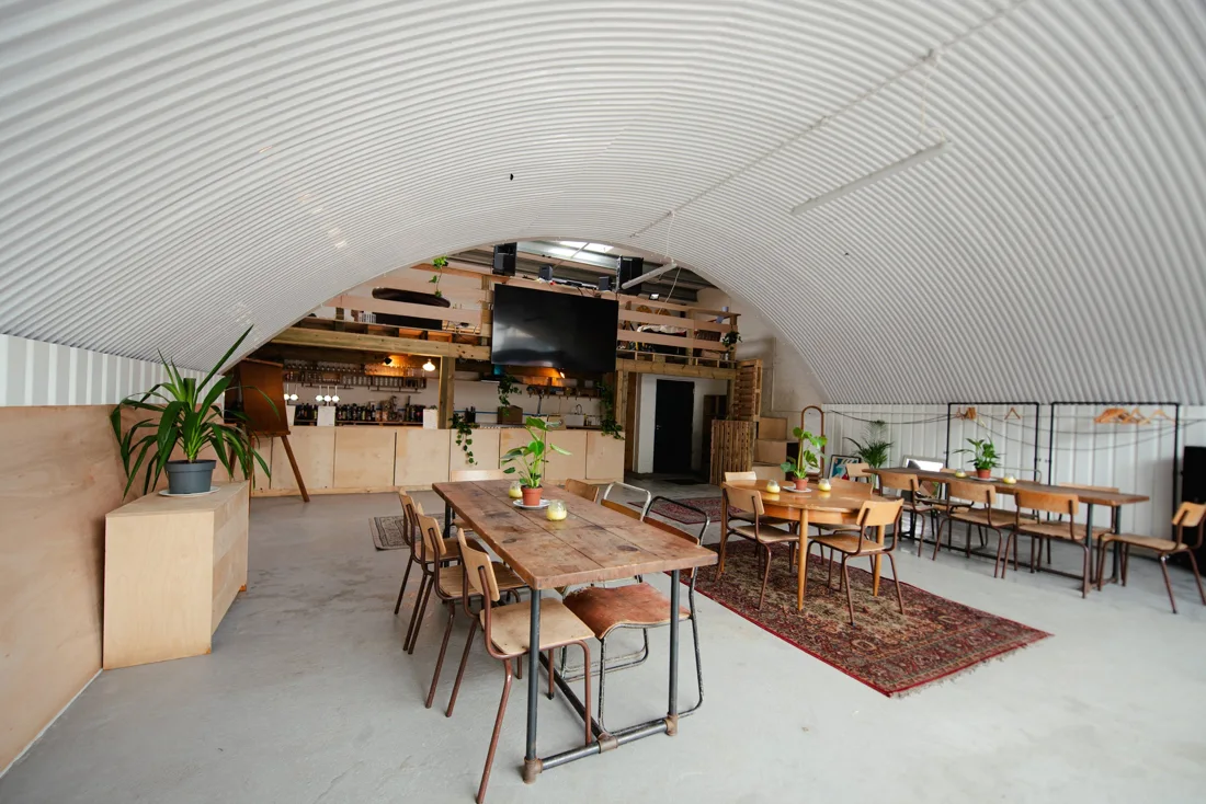 Bread & Butter Arch corrugated-steel arch interior with tables, rug and bar