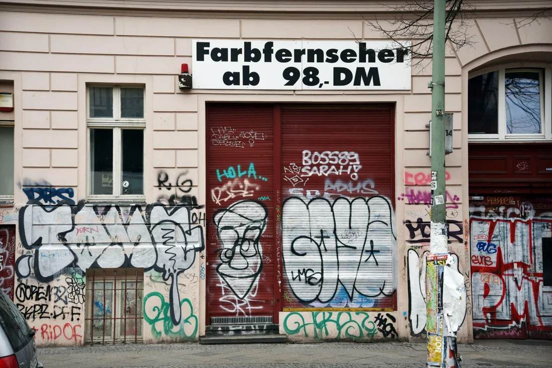 Bulbul Berlin street front: graffitied shutters under old Farbfernseher sign
