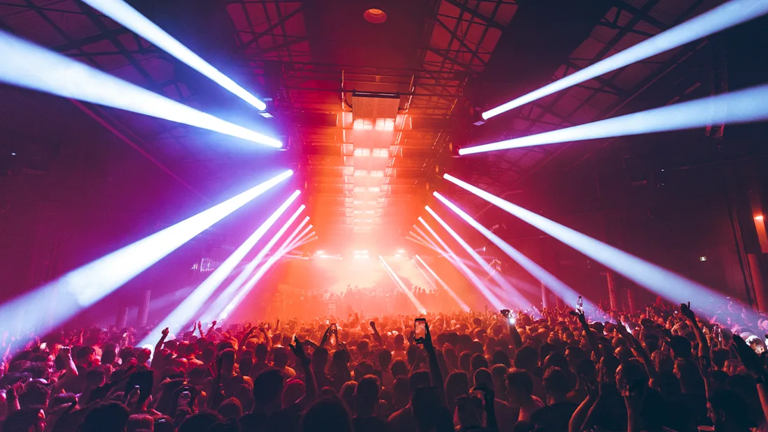A packed music crowd beneath white and pink stage lights inside Carriageworks' industrial warehouse