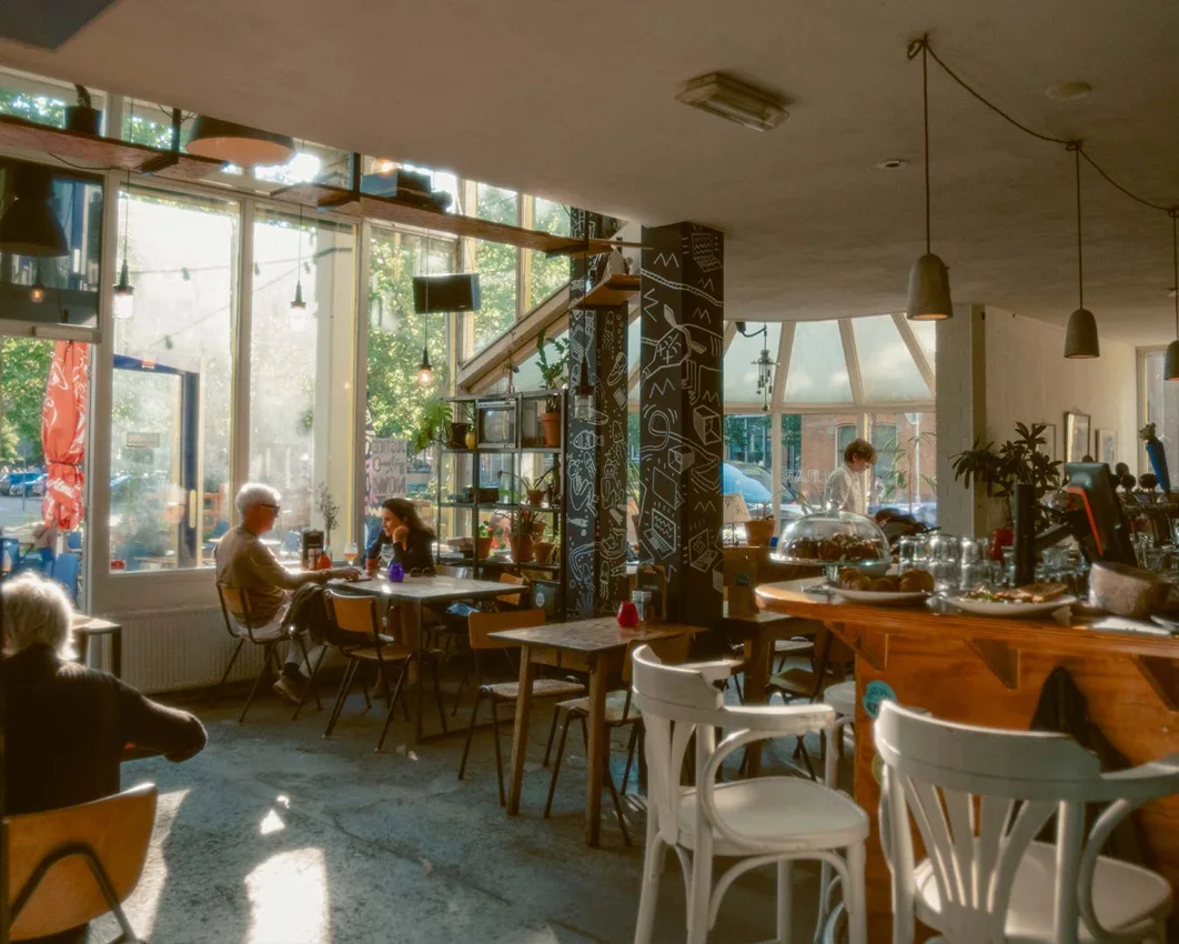 Cinetol sunlit Tolbar cafe with wooden bar, chalk-drawn pillars and tables