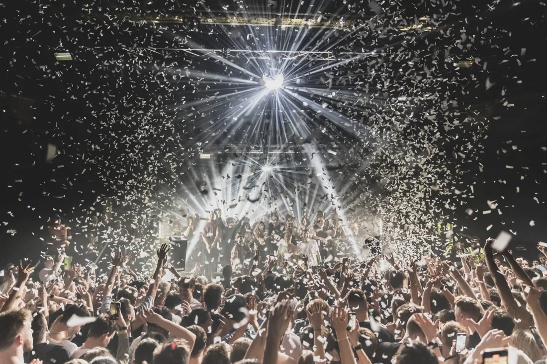 A packed Electric Brixton crowd beneath a mirror ball and confetti, facing the DJ booth