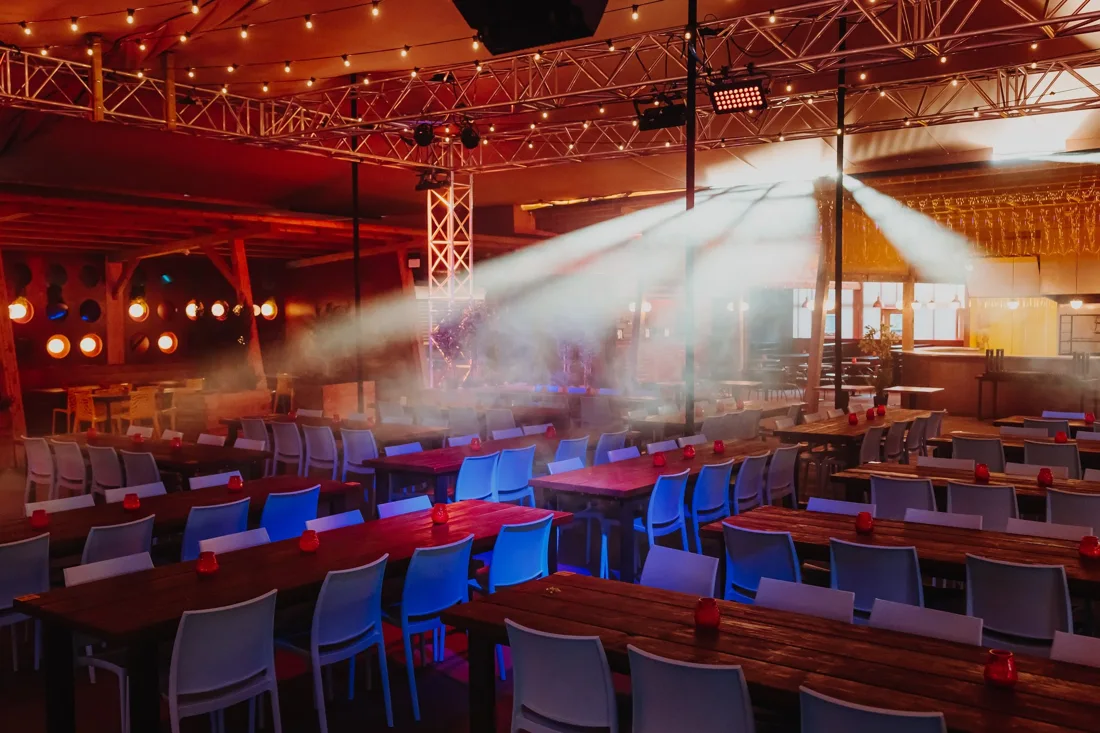Freight Brixton hall with long tables, lighting truss, haze and string lights