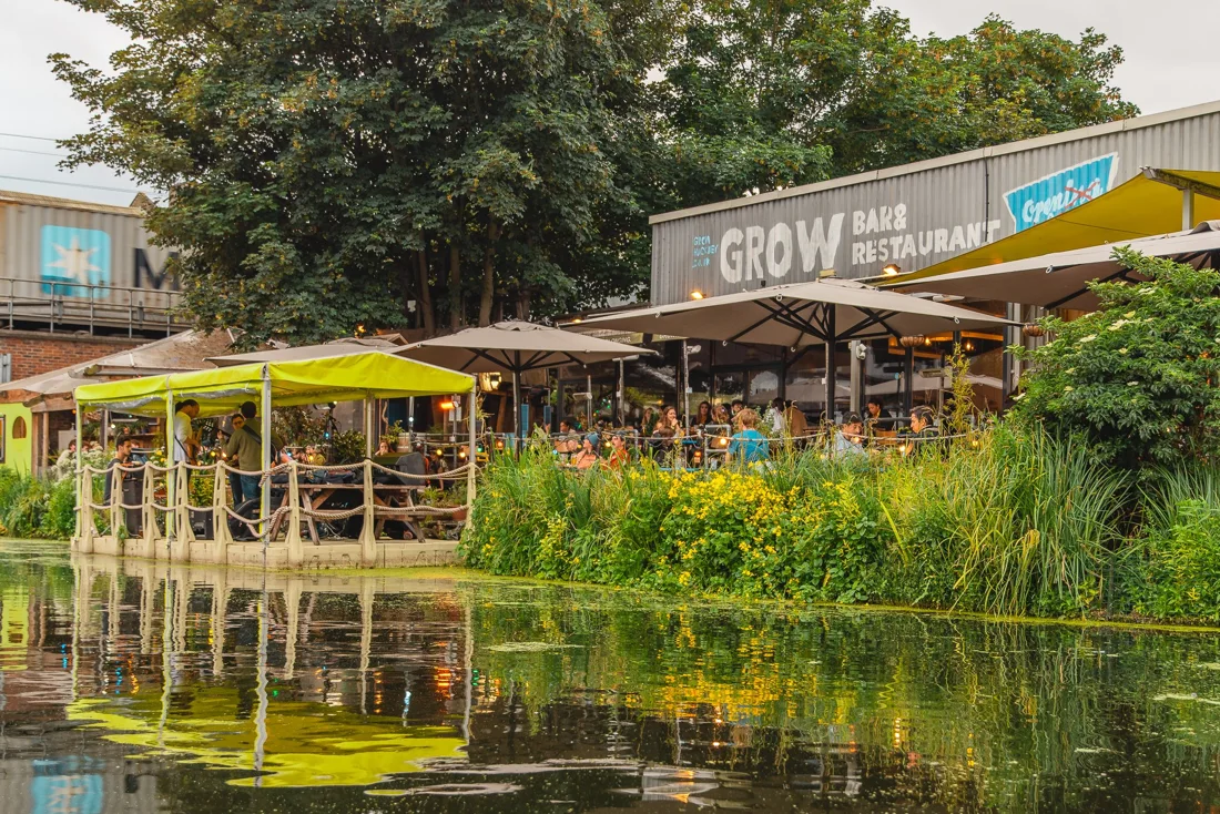 Grow canalside bar building with GROW sign, umbrellas and diners