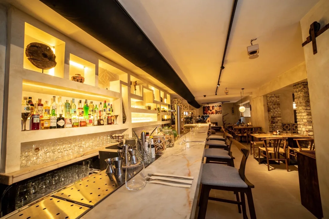 Hearth long marble bar with backlit bottle shelves and stools