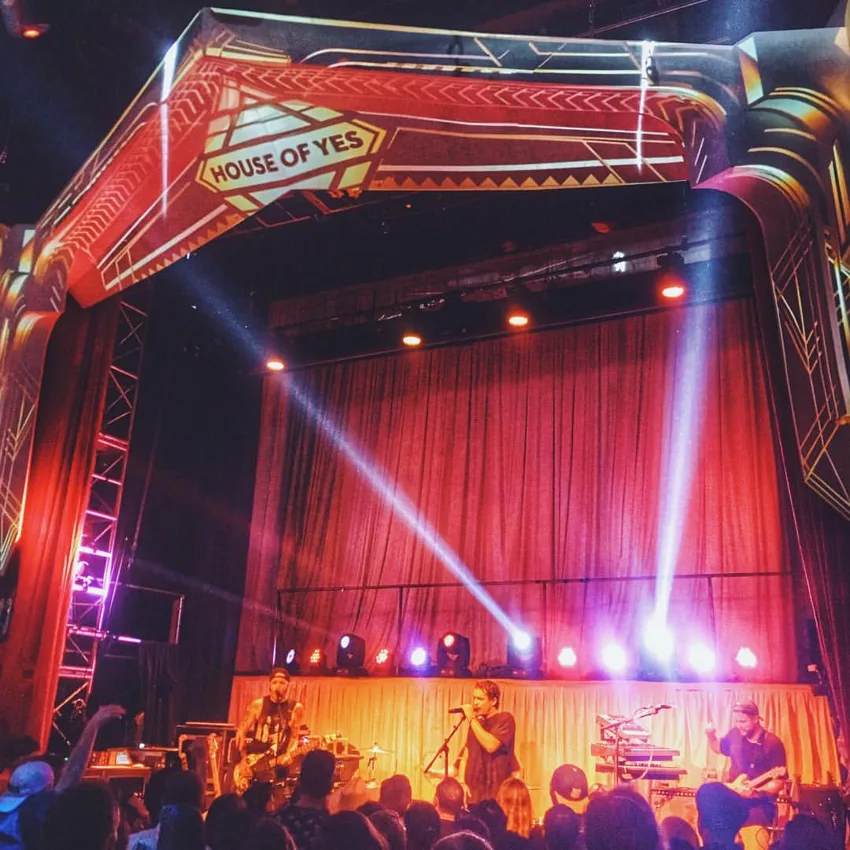 House of Yes stage under its branded proscenium arch and red curtain