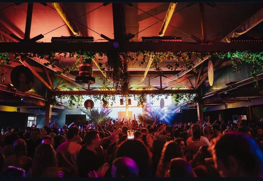 Ijland hall under steel roof beams and hanging plants, crowd at the stage