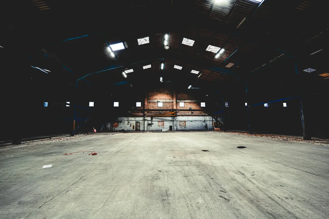 Ironworks vast empty warehouse floor, brick back wall, skylights
