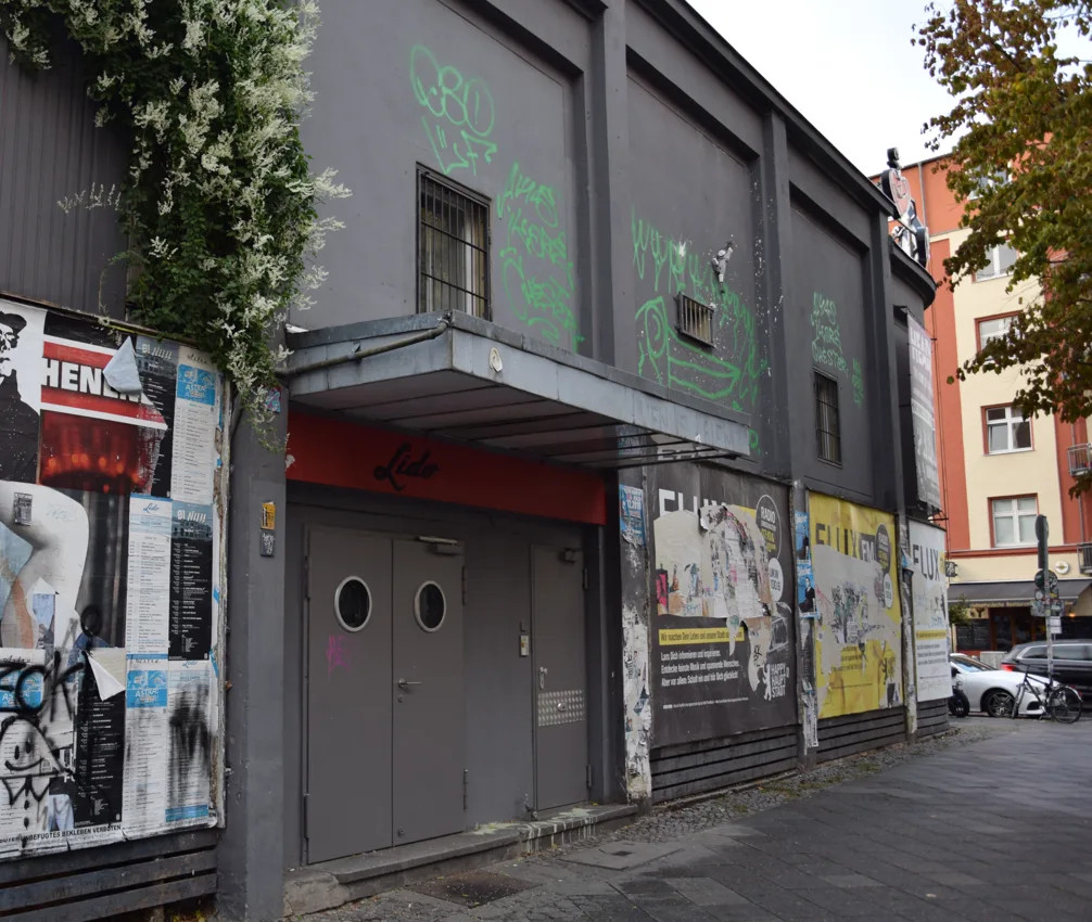 Lido Berlin grey street entrance with red Lido sign and postered walls