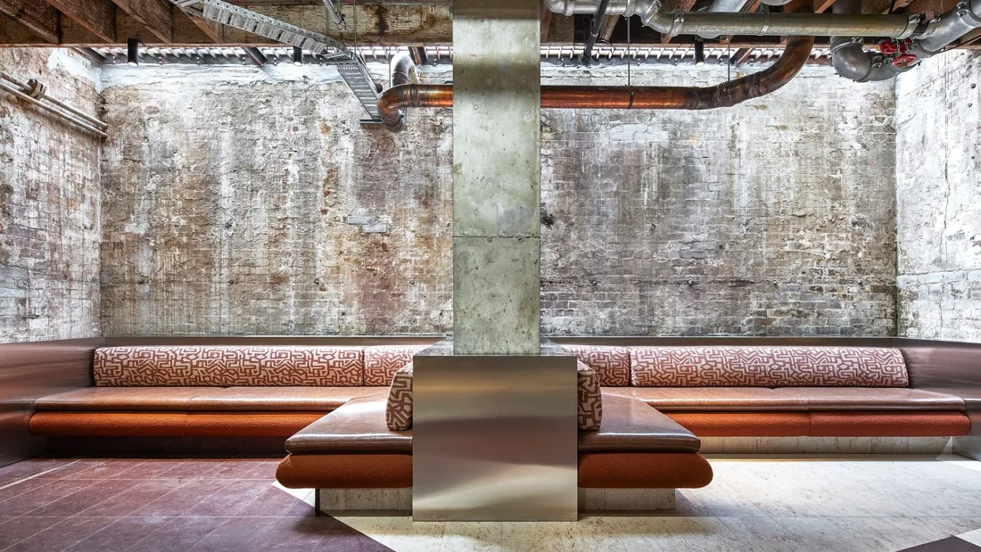 Machine Hall exposed-brick basement lounge with banquettes and copper pipework