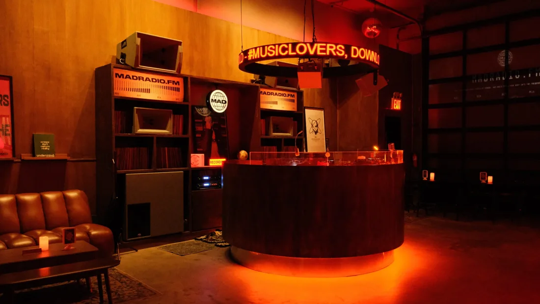 MAD Radio NYC circular wooden DJ booth, record shelves and leather sofa