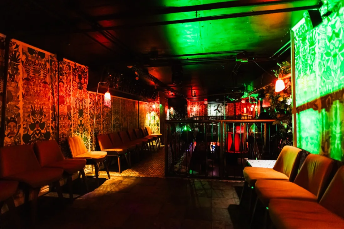 Mehanata Bar lounge with patterned wallpaper and orange banquettes