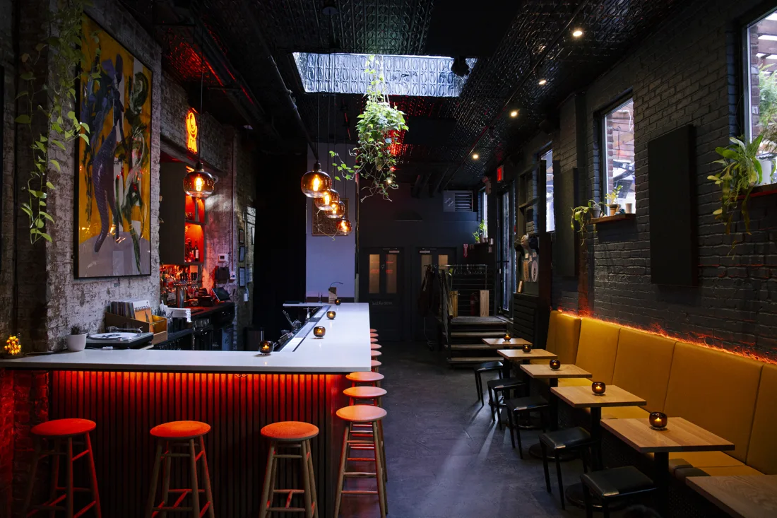 Moondog Hifi listening bar with orange-lit counter, stools and yellow banquettes