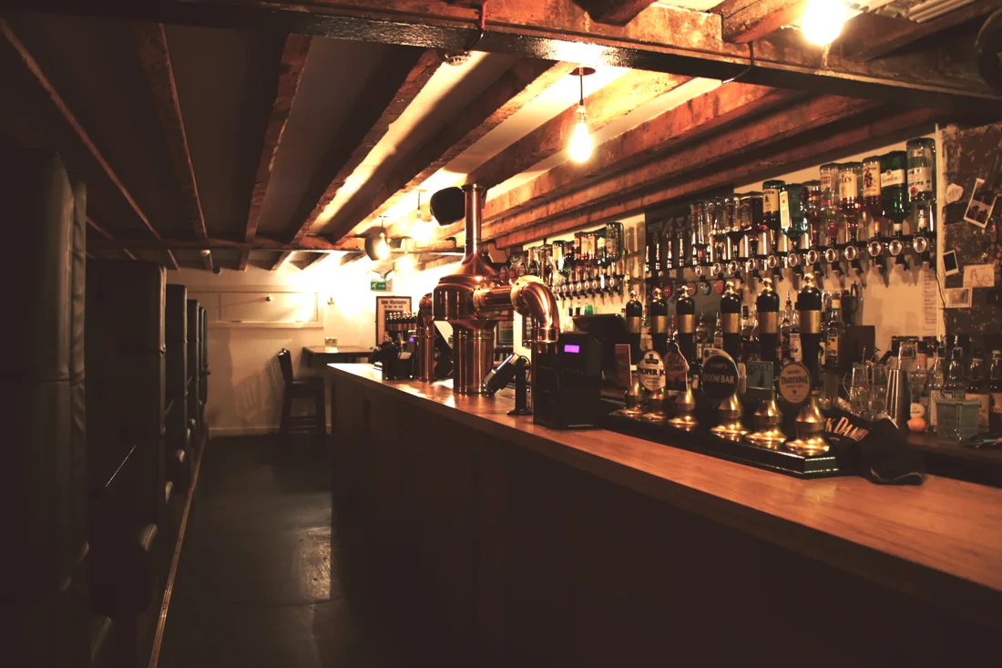 New Cross Inn bar with beamed ceiling, pumps and back bar