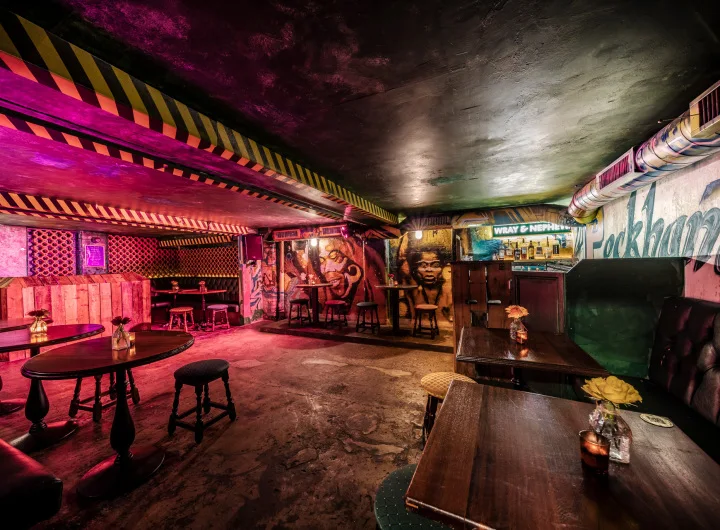 Prince of Peckham basement bar with murals, tables and pink lighting