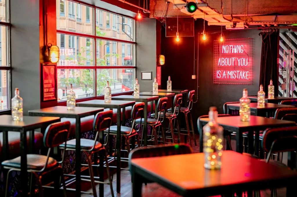 Queen Of Hoxton ground-floor bar with high tables and red neon sign