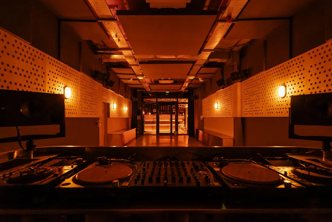 radial main room seen over the DJ booth, amber perforated wood walls