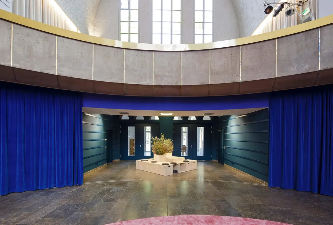 Start.Bahn church hall with blue velvet curtains and concrete gallery ring