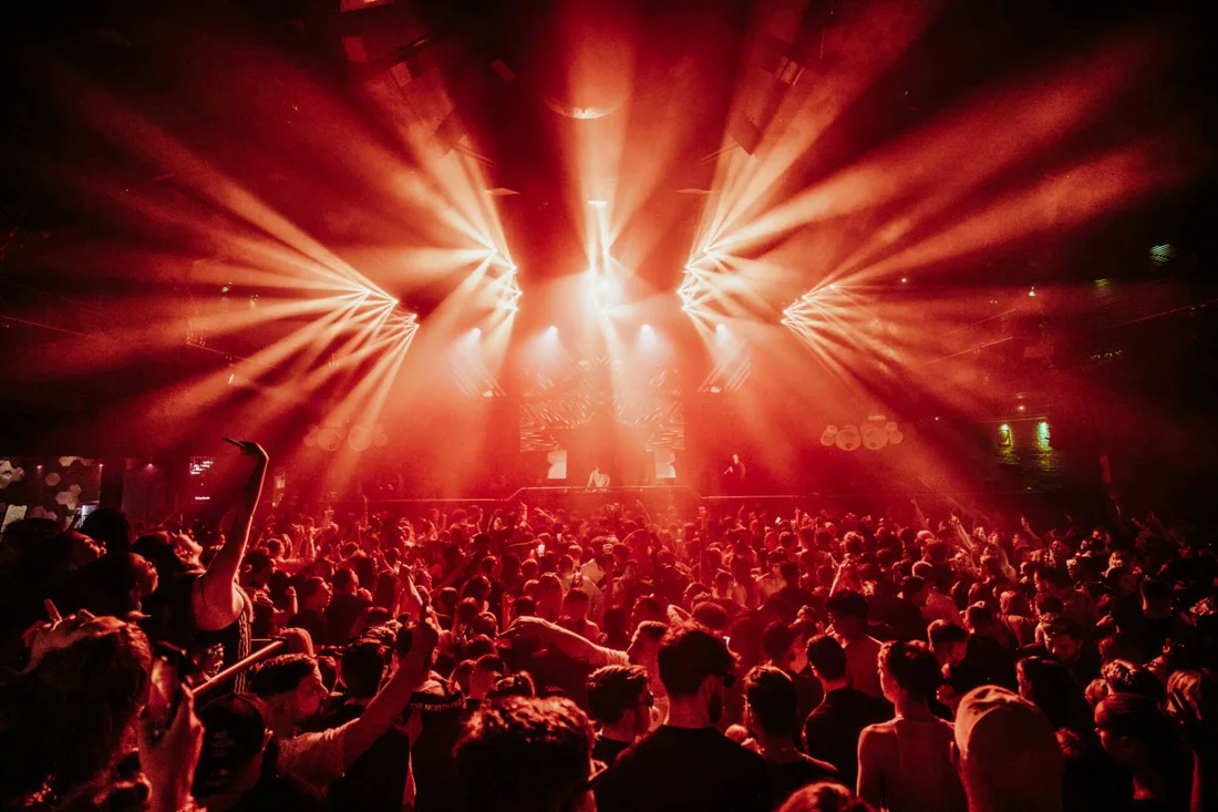 Studio 338 packed main room under red beam lights facing the stage