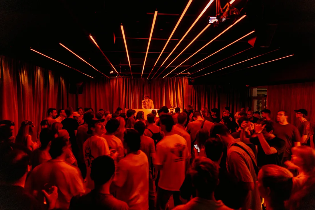 DJ and dance crowd under red ceiling lights inside The Abercrombie, Sydney