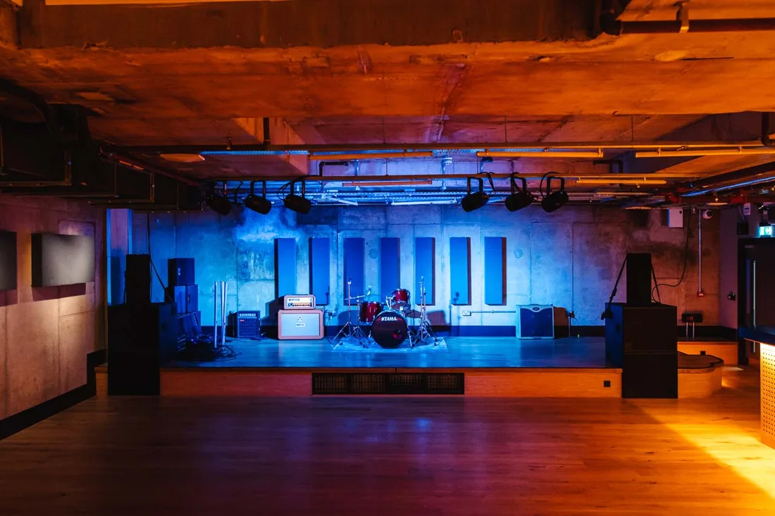 The Lower Third basement live room with stage, drum kit and blue lights