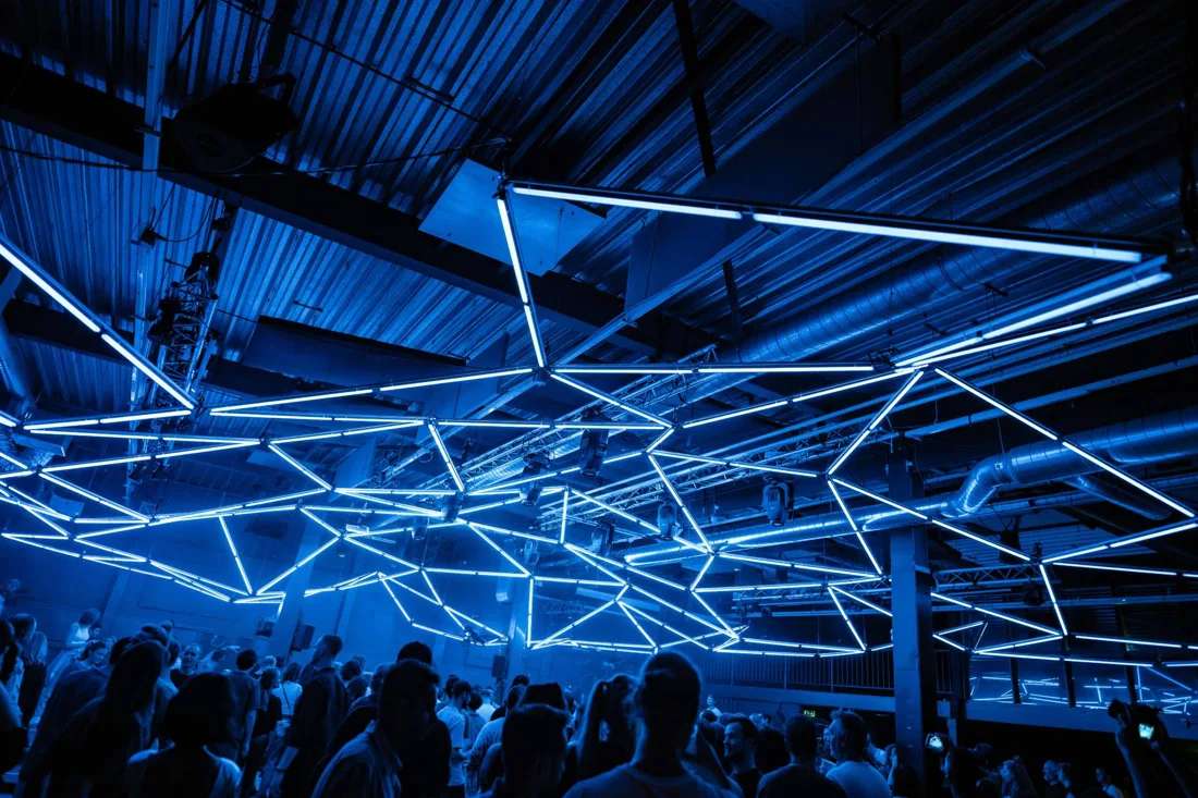 THE OTHER SIDE industrial hall with web of blue neon tubes over dancefloor