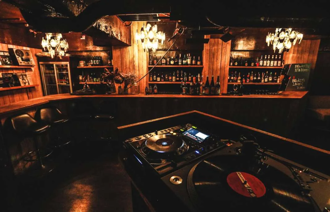 The Room wood-panelled bar with chandeliers and turntables in front