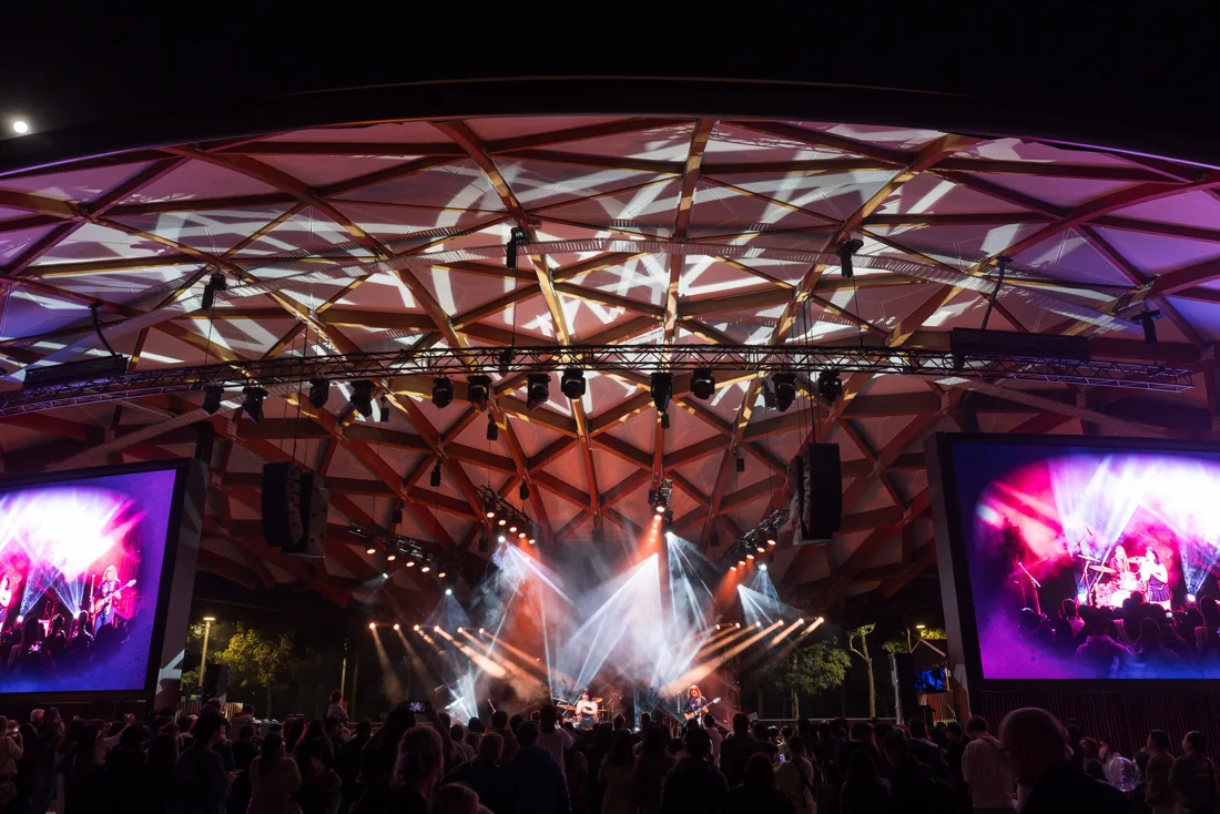 Vivid Sydney festival performers and crowd beneath the illuminated Tumbalong Park stage shell