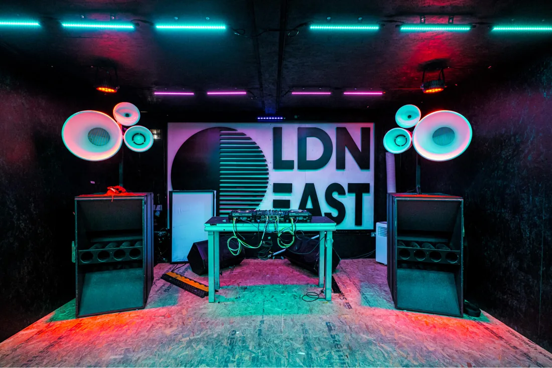 Upper East dark container room with DJ booth and horn speaker stacks