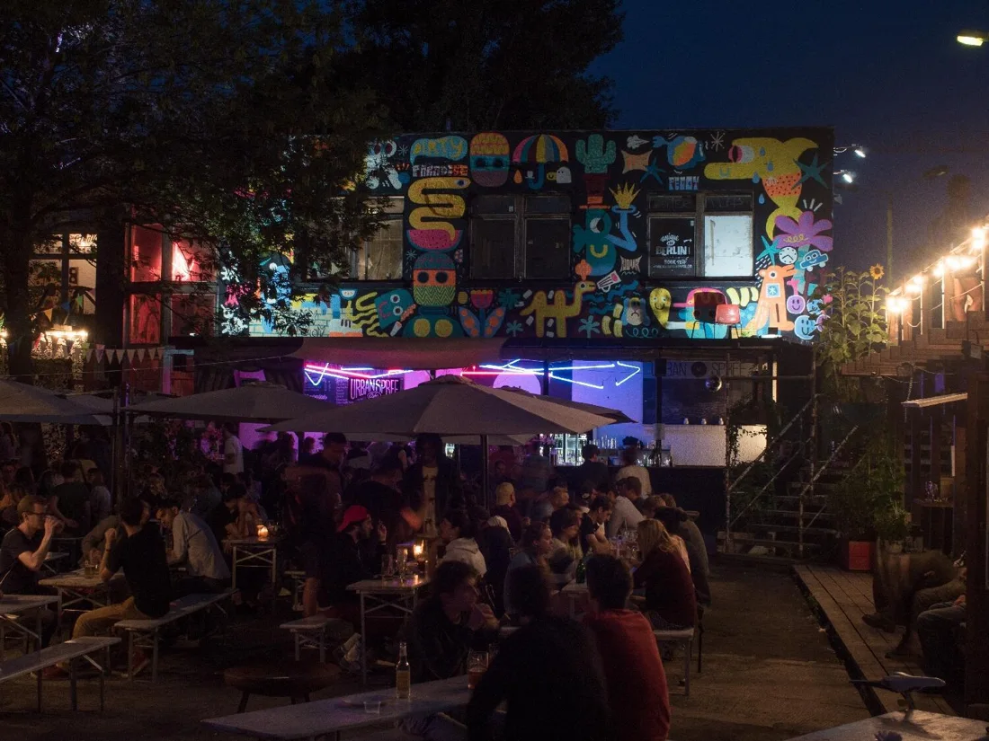 Urban Spree biergarten at night below mural-covered building